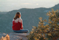 woman sitting on a rock looking out over an expansive mountain view